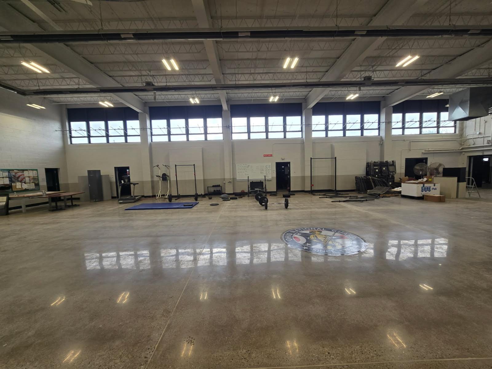 The full drill hall at the Ohio Army National Guard armory, polished floor reflecting the clerestory windows and freshly painted block walls