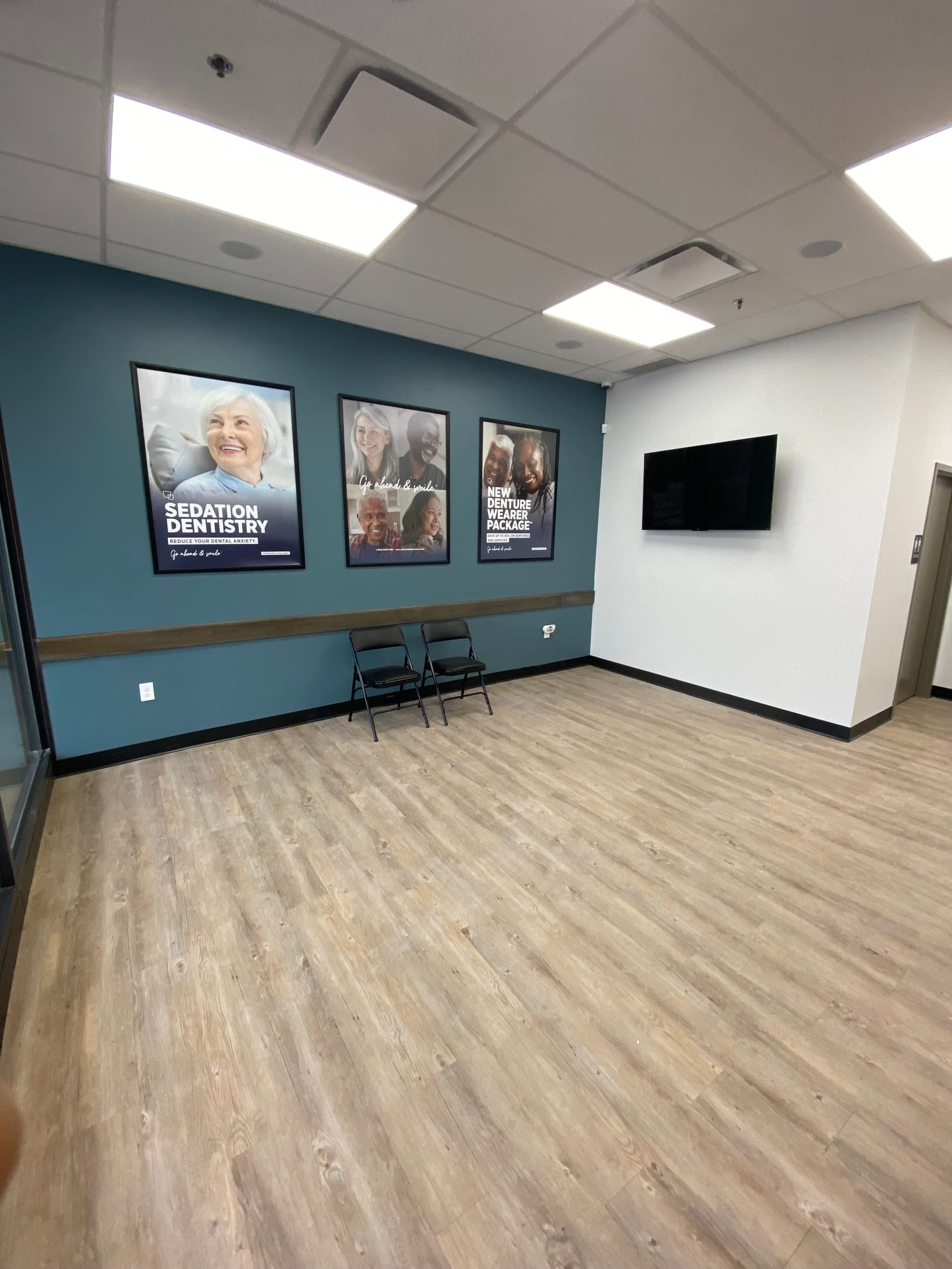 Repainted patient corridor at Affordable Dentures and Implants, navy accent wall and wood-look floor with clean cut lines against the white ceiling
