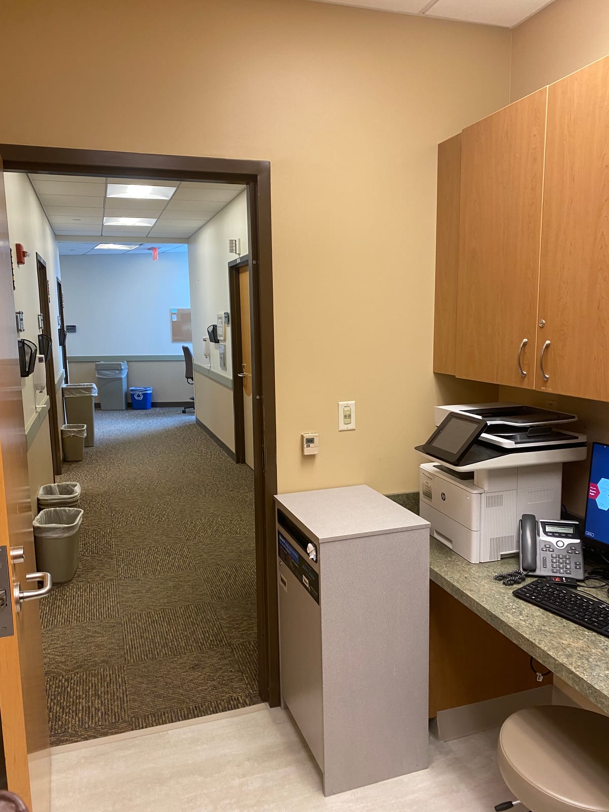 Painted hospital corridor with patient room doors and carpet flooring in an occupied wing at University Hospitals Ahuja Medical Center