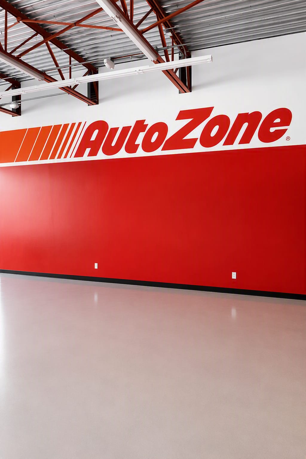 Finished high-bay retail interior with a fully coated wall, brand band and exposed structural steel deck