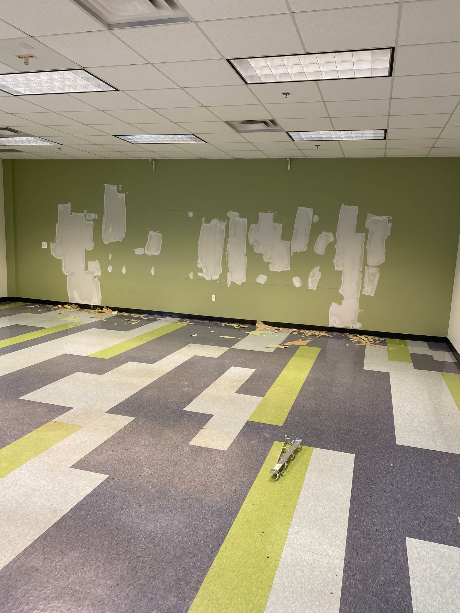 Painted feature wall at Blossom Hill Adult Daycare, white lettering over a green ground with a grey and lime angular graphic