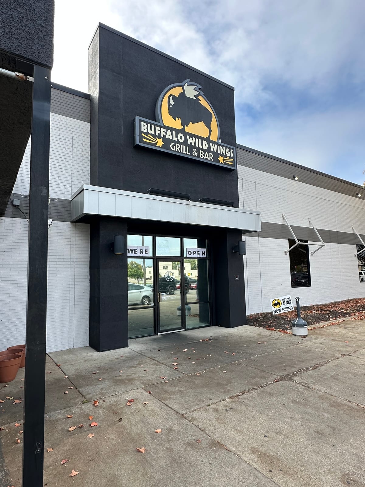 Repainted Buffalo Wild Wings entrance and storefront with a WE'RE OPEN sign in the door