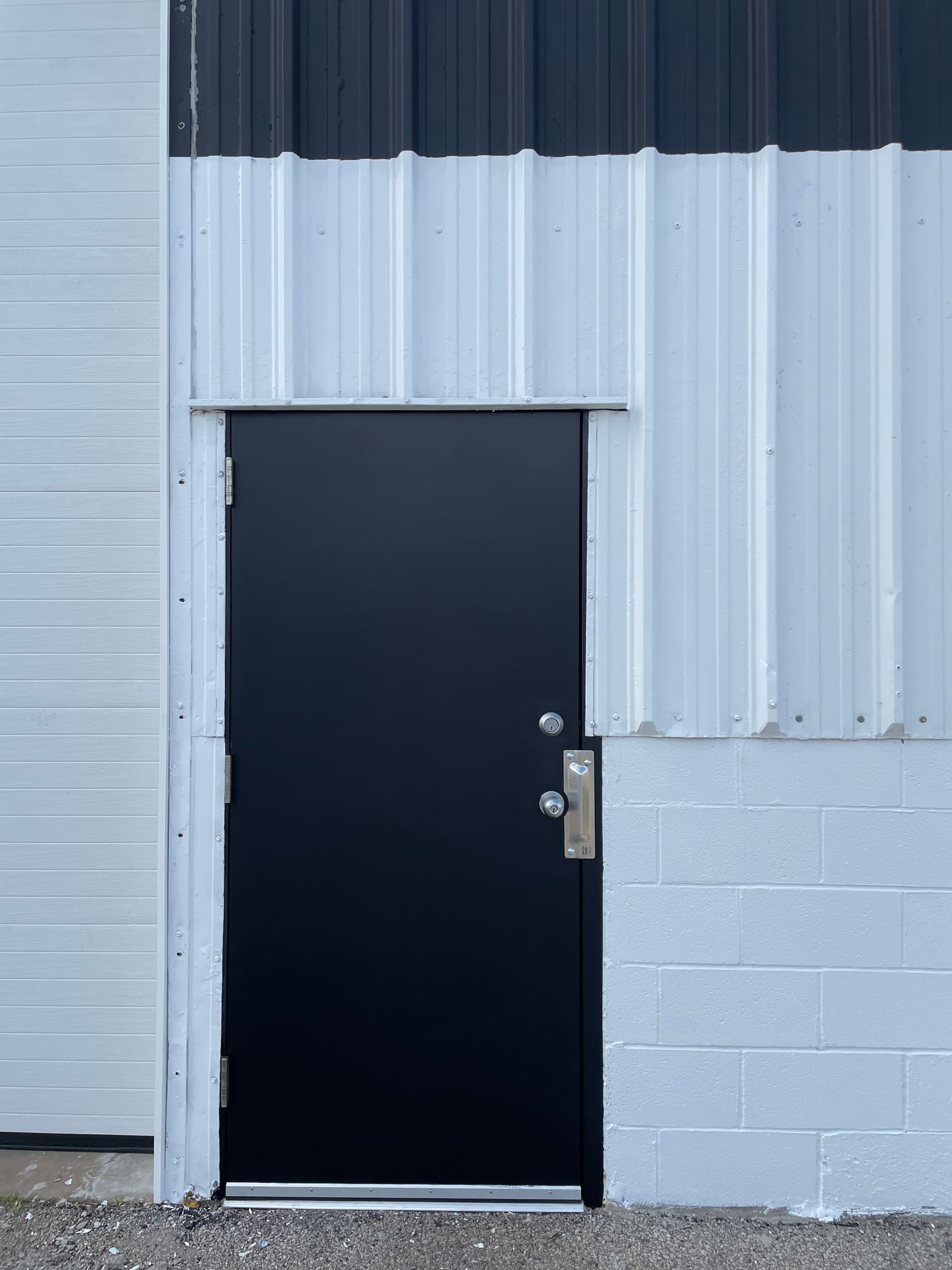 Repainted metal siding at Lambert Buick GMC, white panels with crisp black trim