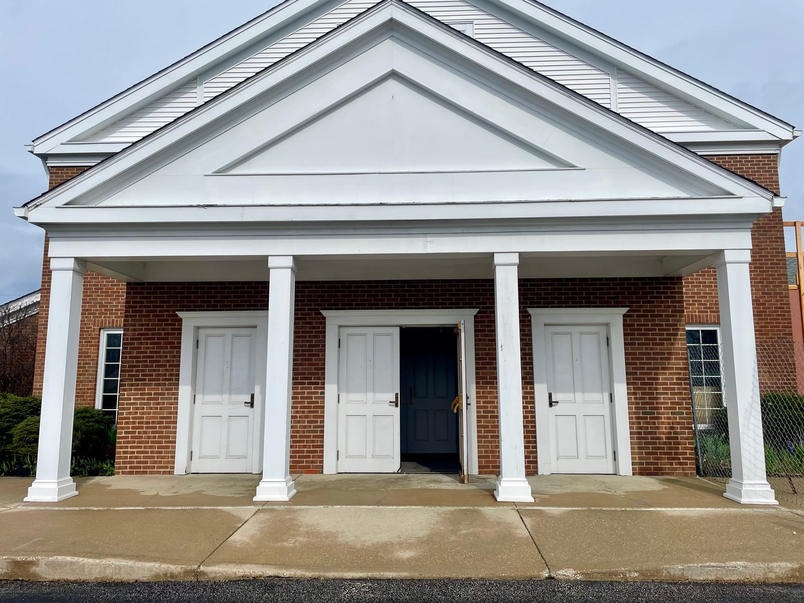 The finished exterior of the Church of the Western Reserve, white portico and columns against red brick