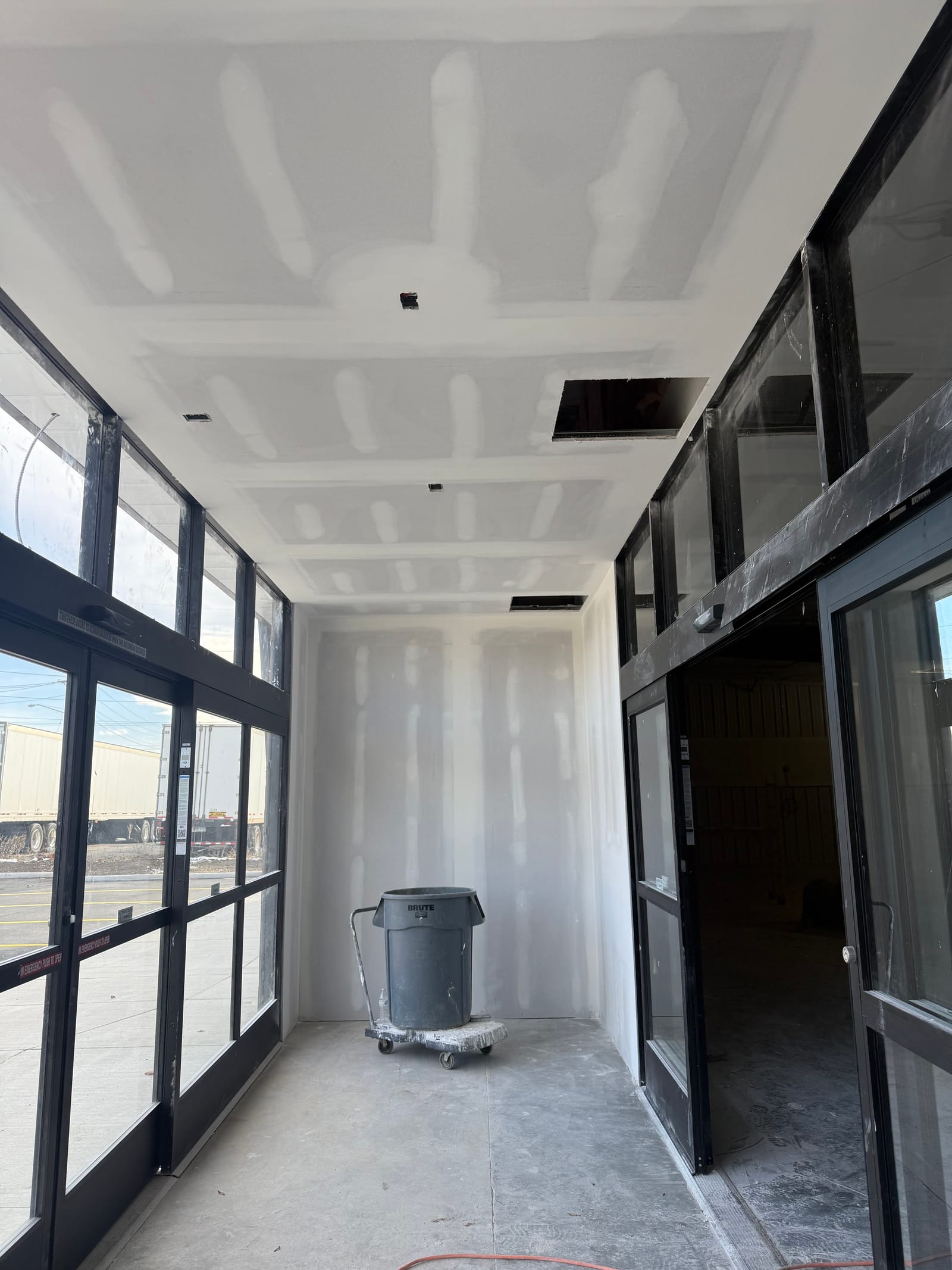 Finished white walls and ceiling running out to the black-framed storefront glass on a Dollar General carpentry and drywall package
