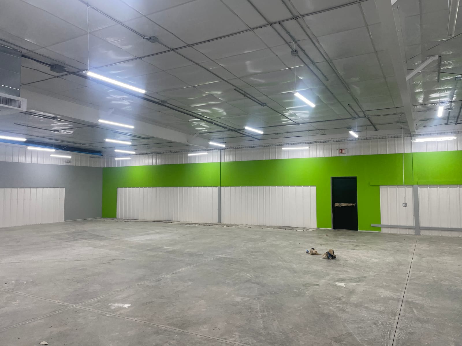 Finished Dollar General sales floor, green accent band over white wainscot under a clean white ceiling deck