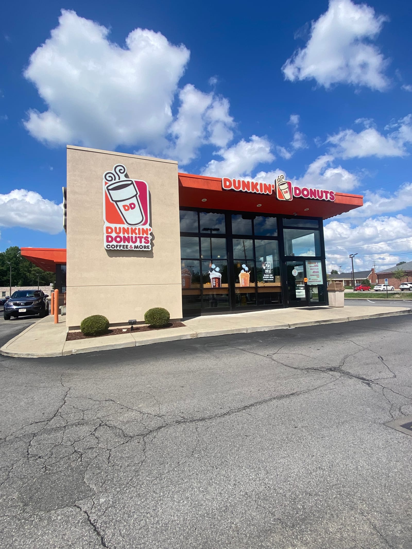 A finished Dunkin' Donuts store from the lot, full sign and repainted orange fascia against blue sky