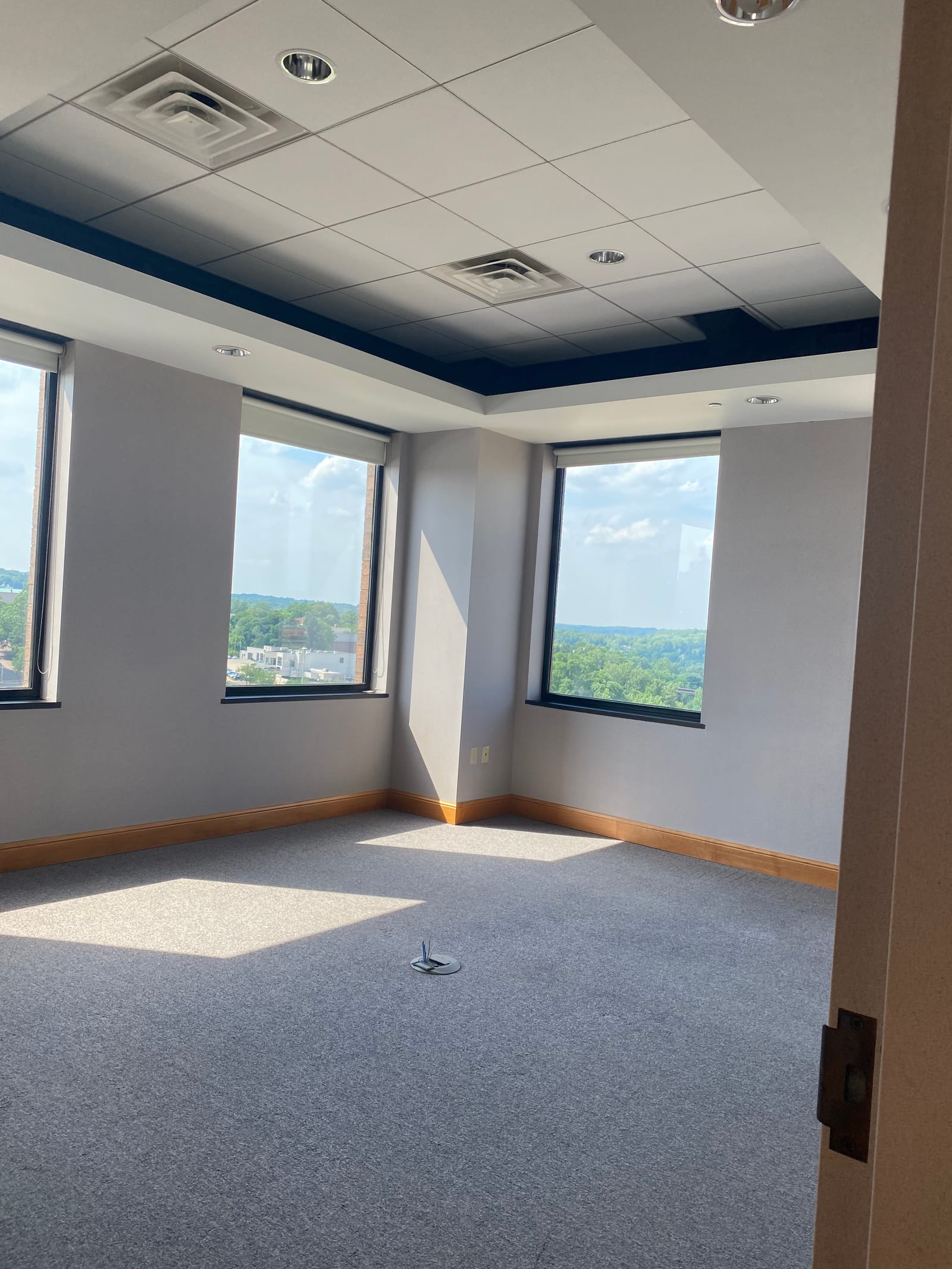 Finished corner office in a law office building, grey walls and a dark recessed ceiling detail beside two city-view windows