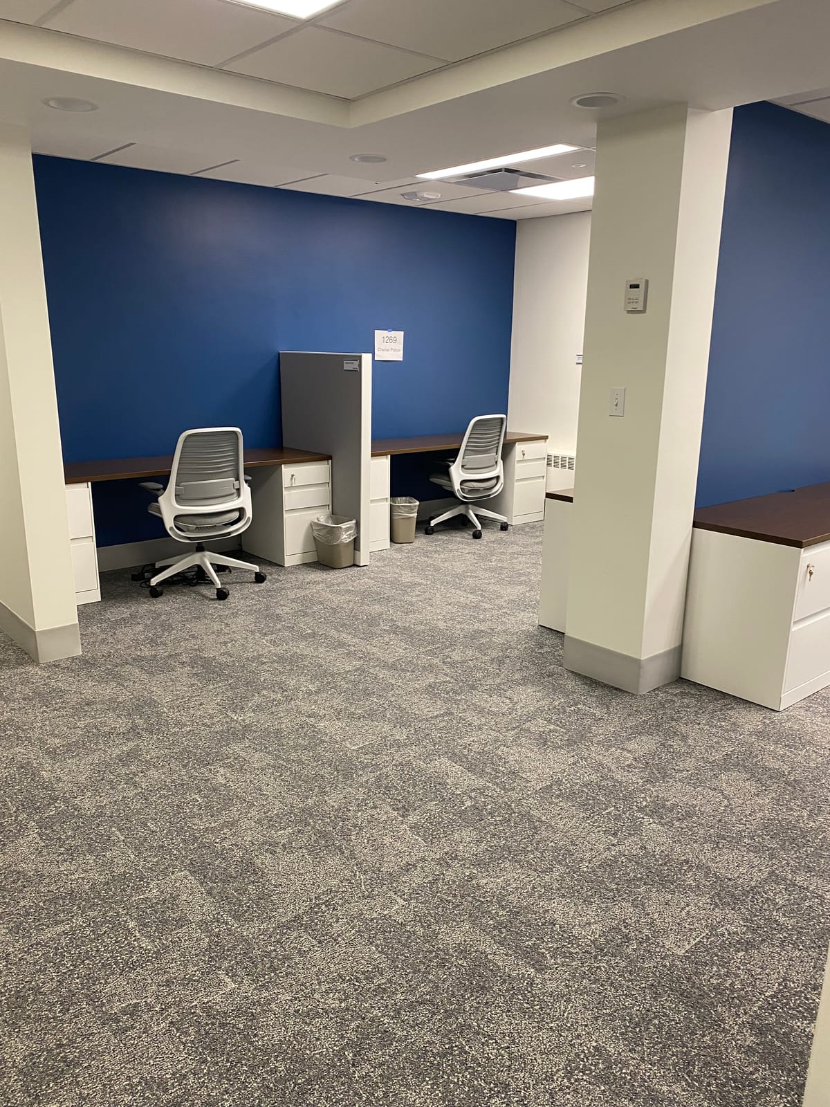 Finished corridor with a continuous painted wall and ceiling, a supply closet door, and no visible seam between old and new drywall work