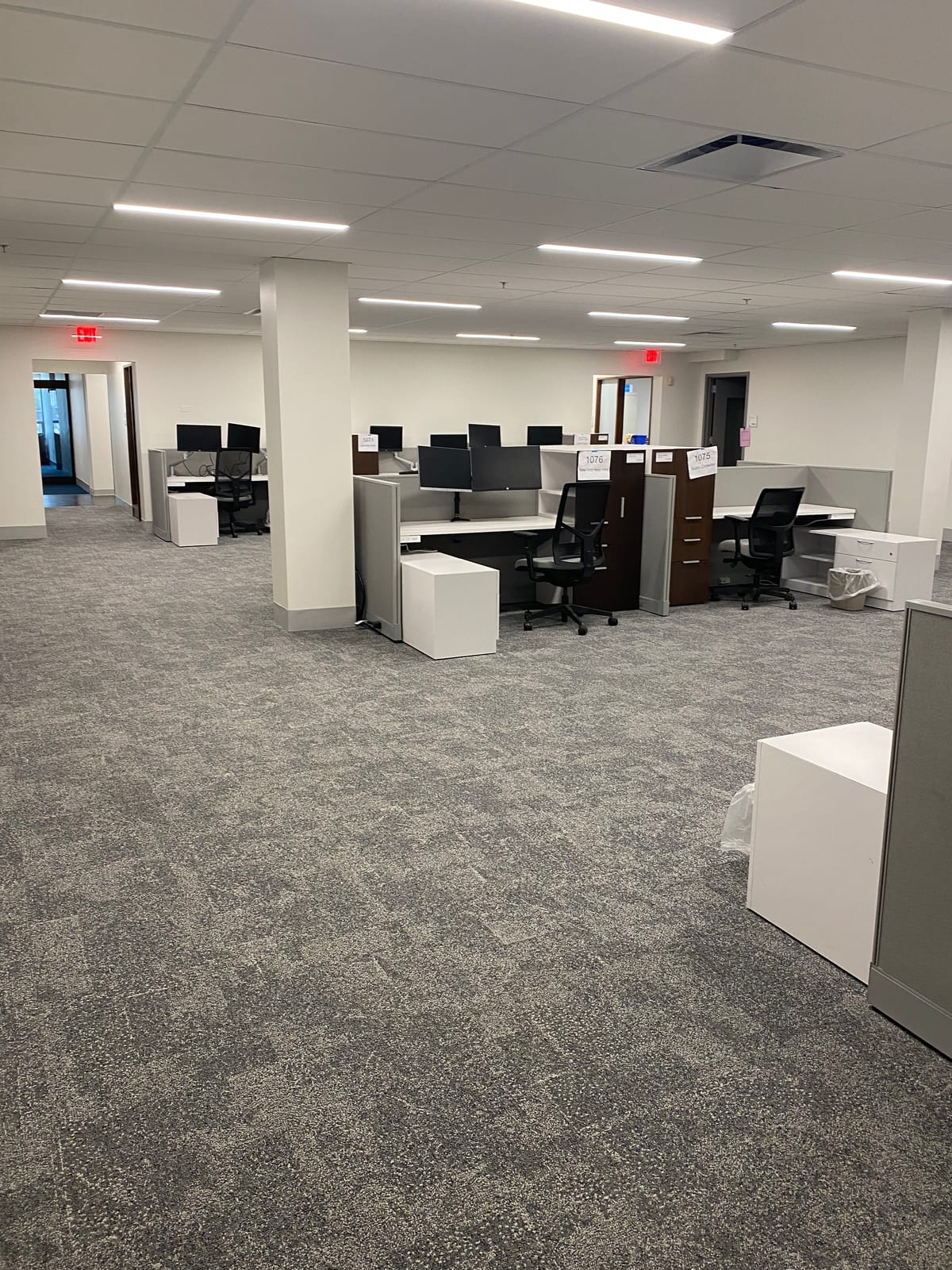 Finished open office space with painted drywall walls and columns, a suspended ceiling grid, and cubicles ready for move-in at a Next Generation corporate office build-out