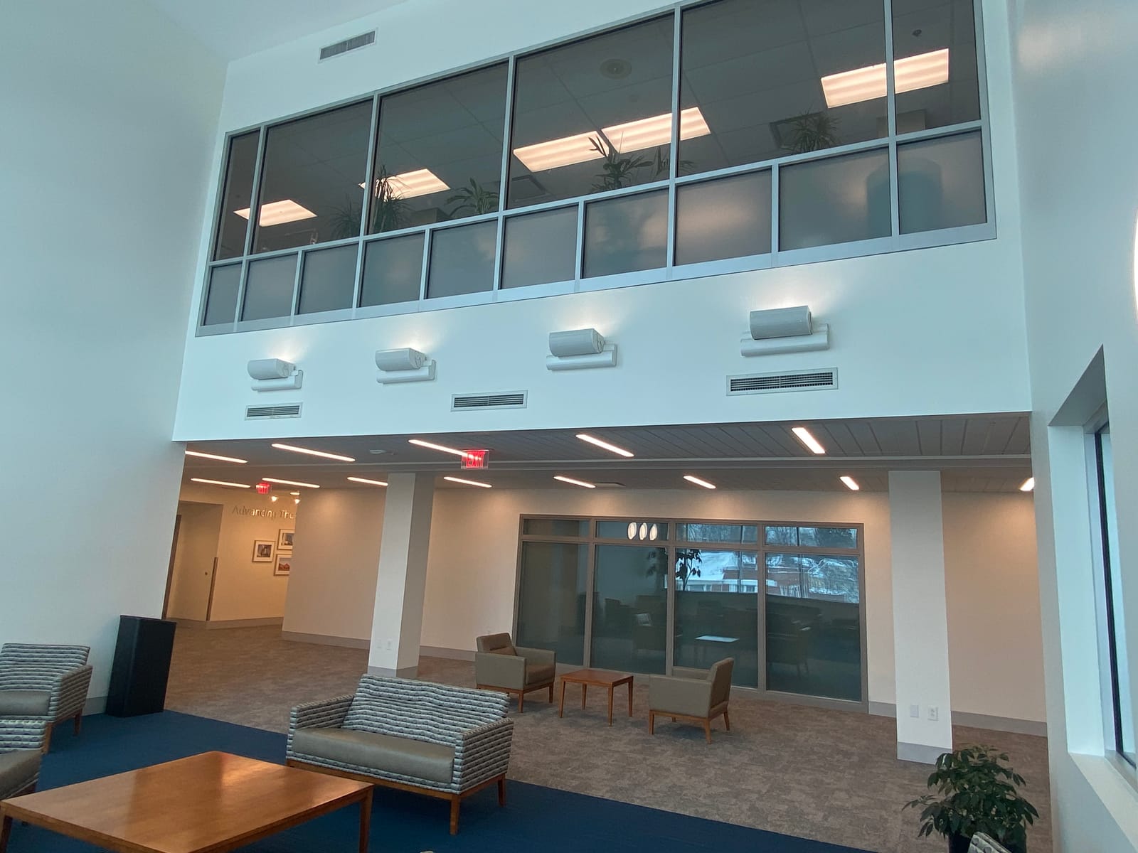 The two-storey atrium at the University Hospitals Management Service Center, pale blue painted walls under clerestory glazing