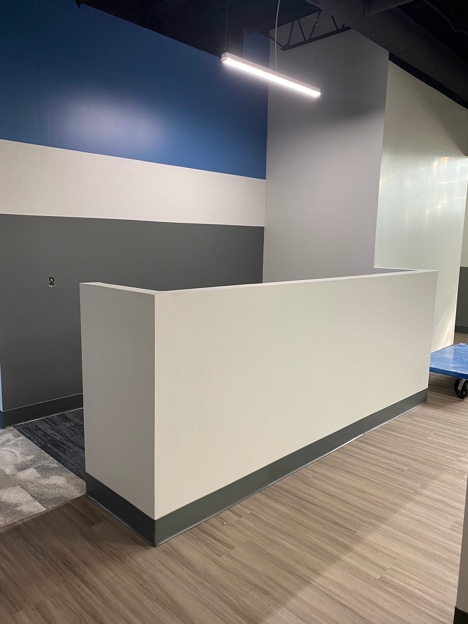 Finished reception desk against a navy and grey two-tone painted wall with new wood flooring