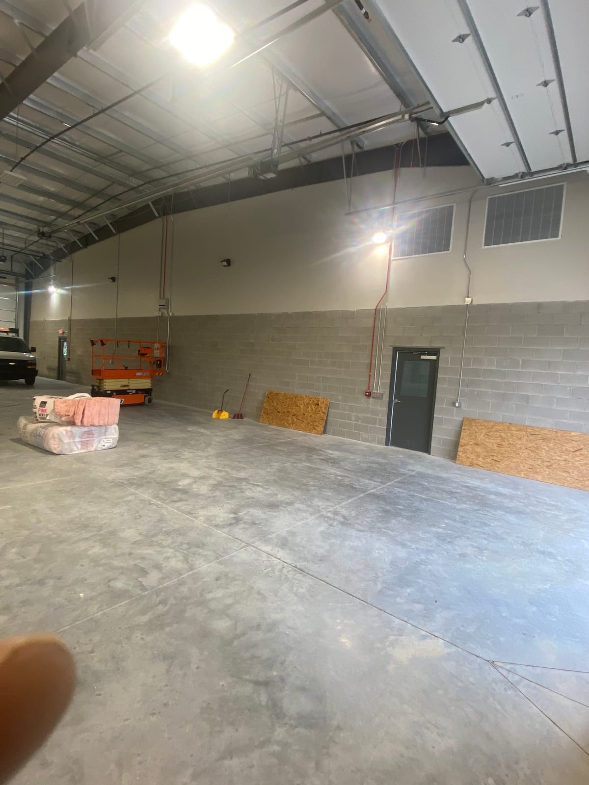 Painted white metal building ceiling deck with exposed structural steel purlins and roof trusses