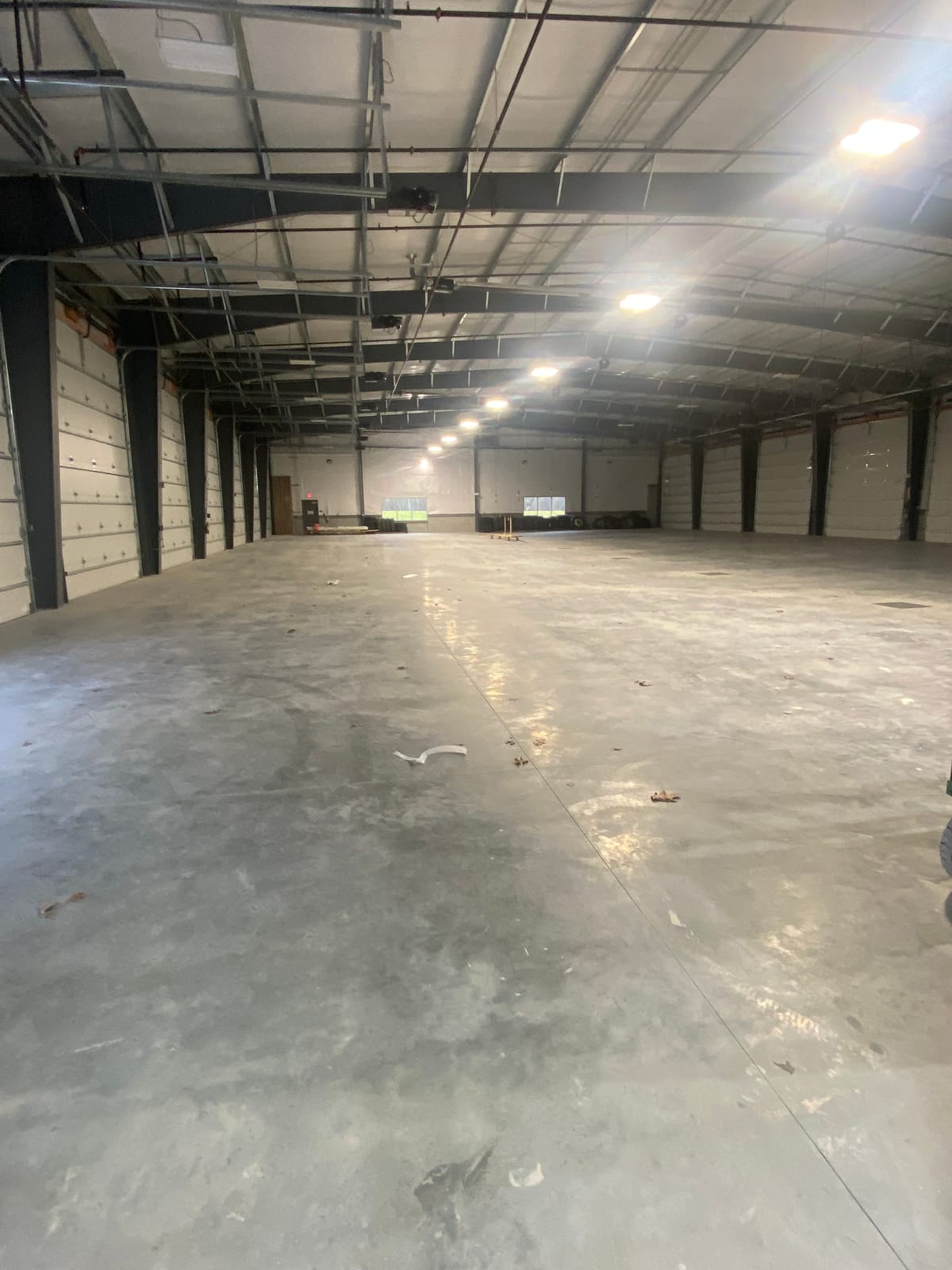 Freshly painted metal building interior with dock doors along both walls and a concrete floor, ready for warehouse use