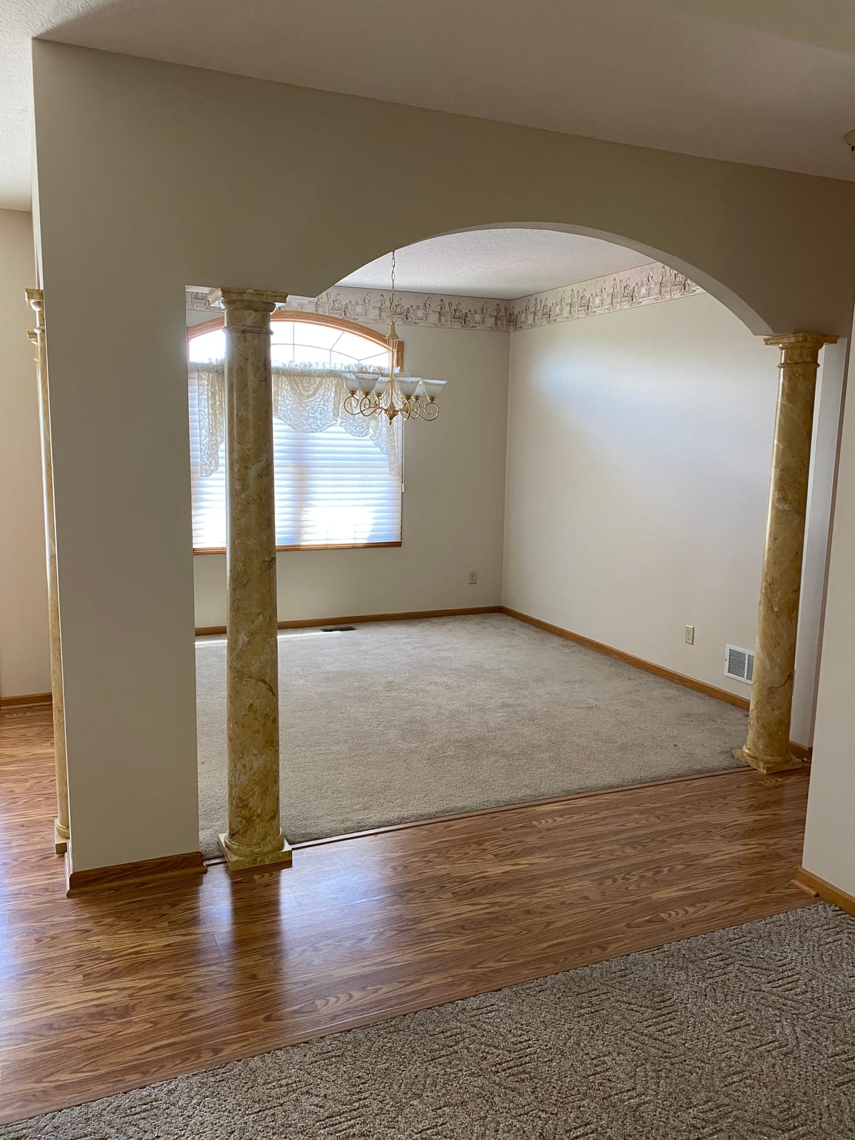 Freshly repainted living room in a Northeast Ohio home with crisp cut lines at the ceiling and baseboard, adjoining hardwood and carpeted floors left clean