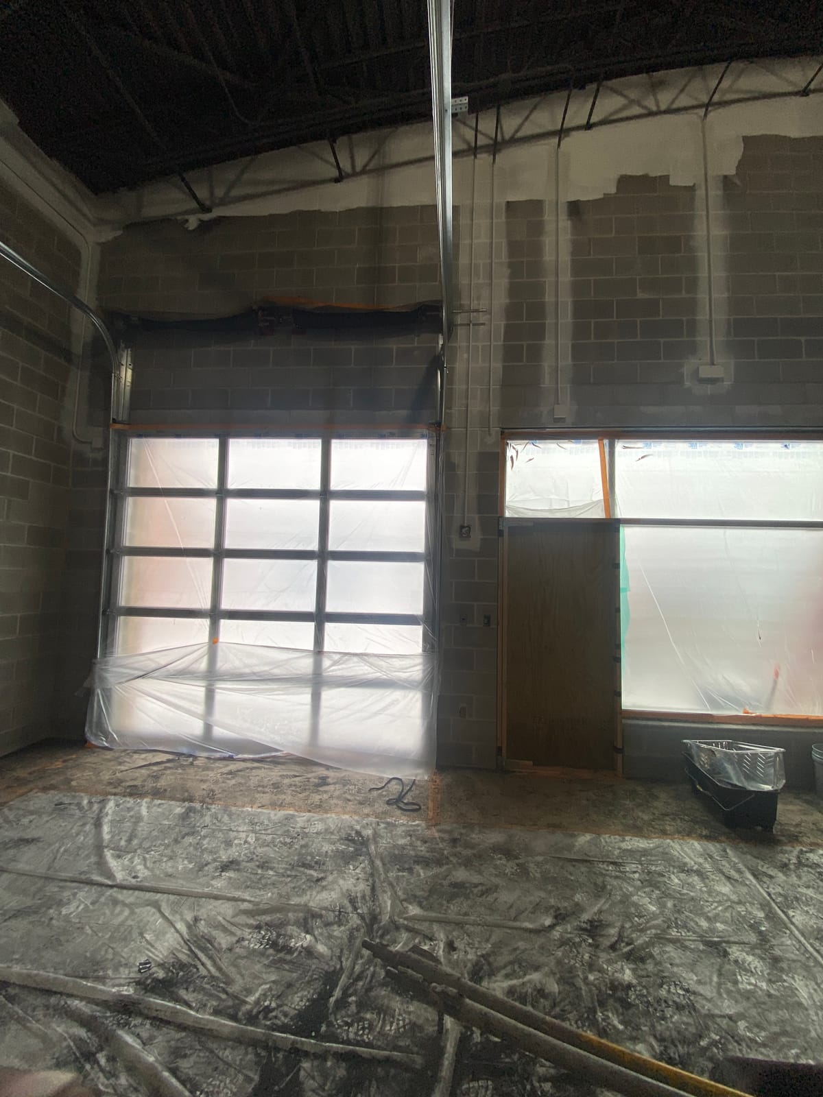 Cinder block wall and garage door window masked and prepared for paint at Theodore Roosevelt High School