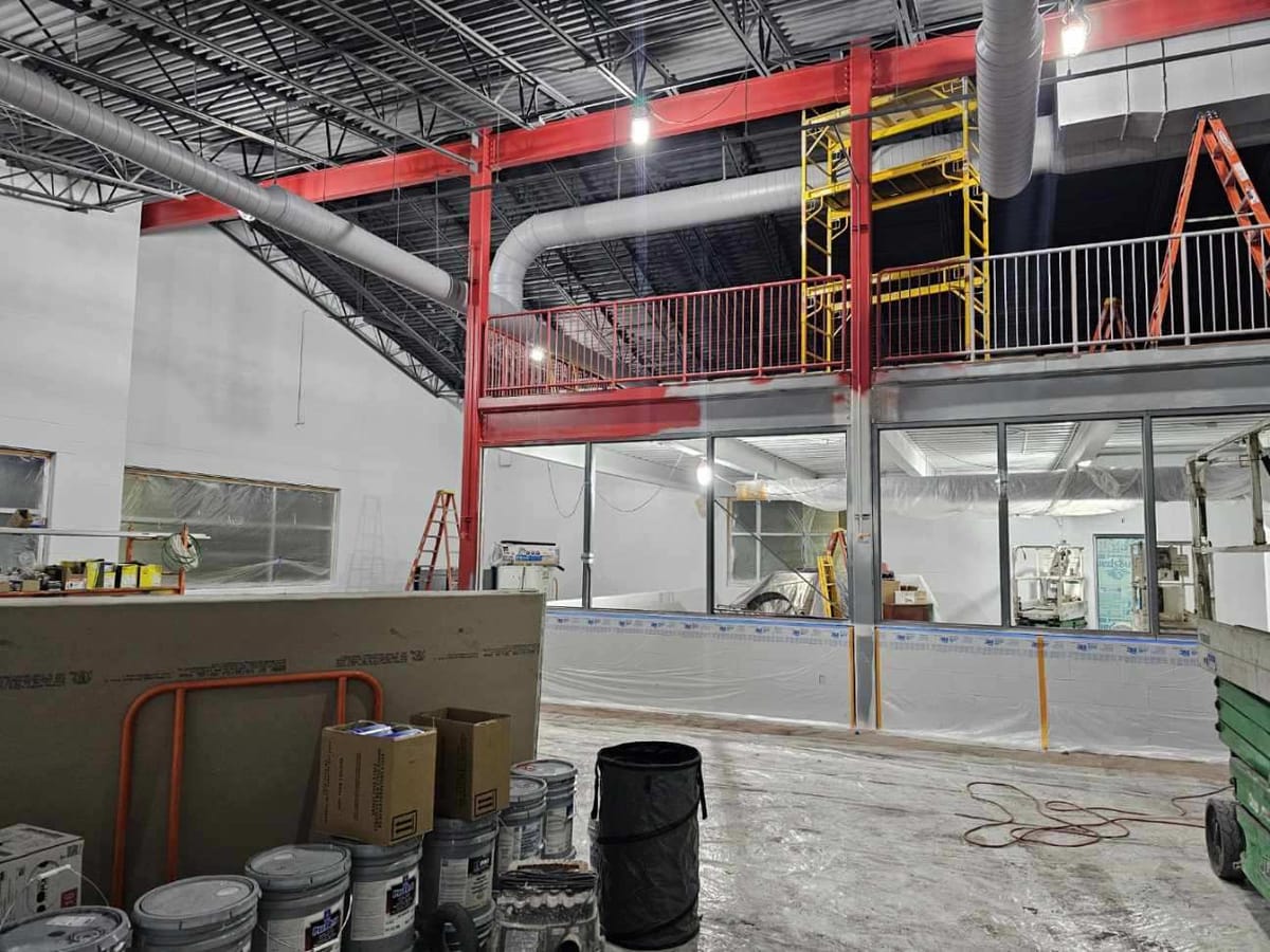 The open commons at Theodore Roosevelt High School, red-painted structural steel columns under a mezzanine and clerestory glazing