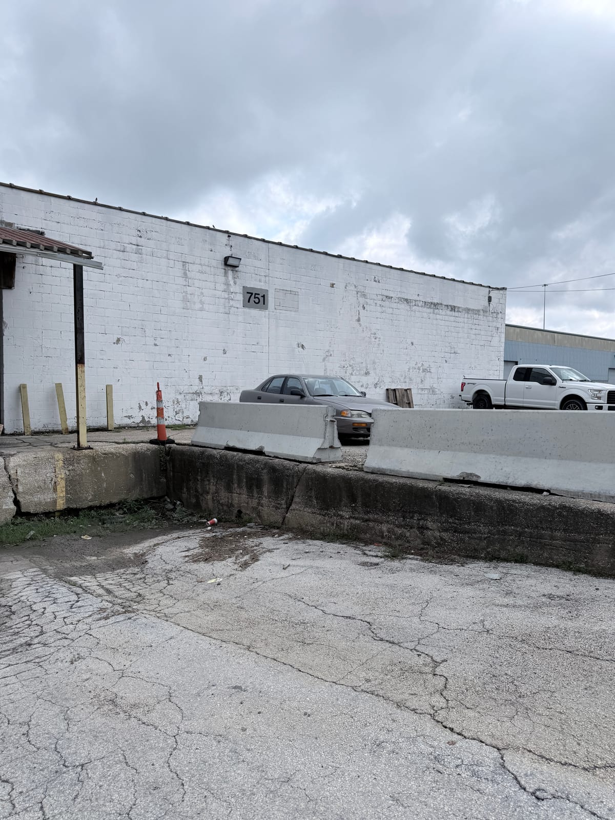 Weathered white CMU and metal industrial building exterior showing wall staining and wear before a coating system is chosen